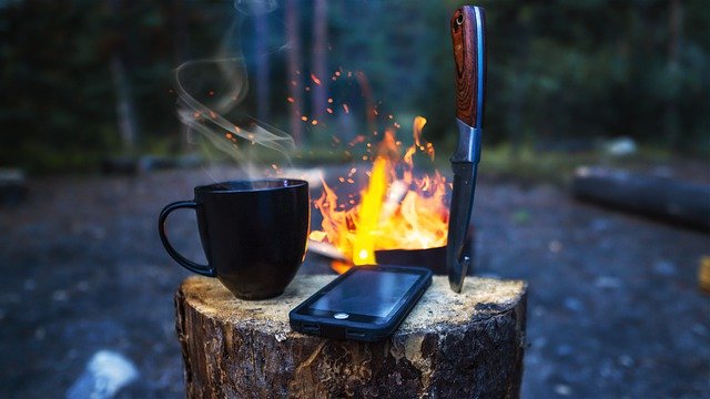 Smartphone with navigation apps for hikers on a tree stump in the forest.
