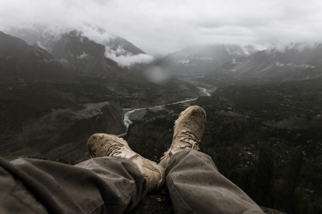 A person sitting with their legs stretched in front of them on the edge of a cliff.