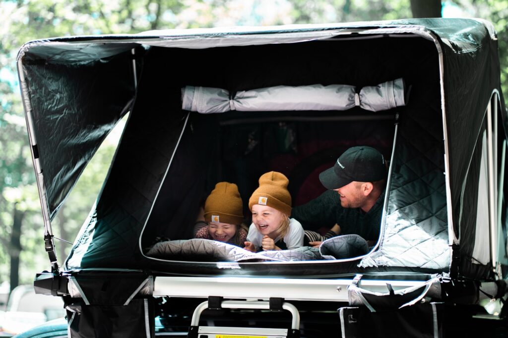 A dad with two kids in a tent laughing 