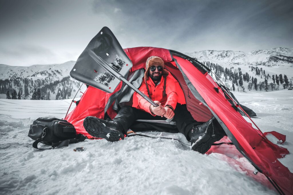 A person in a tent holding a snow shovel.