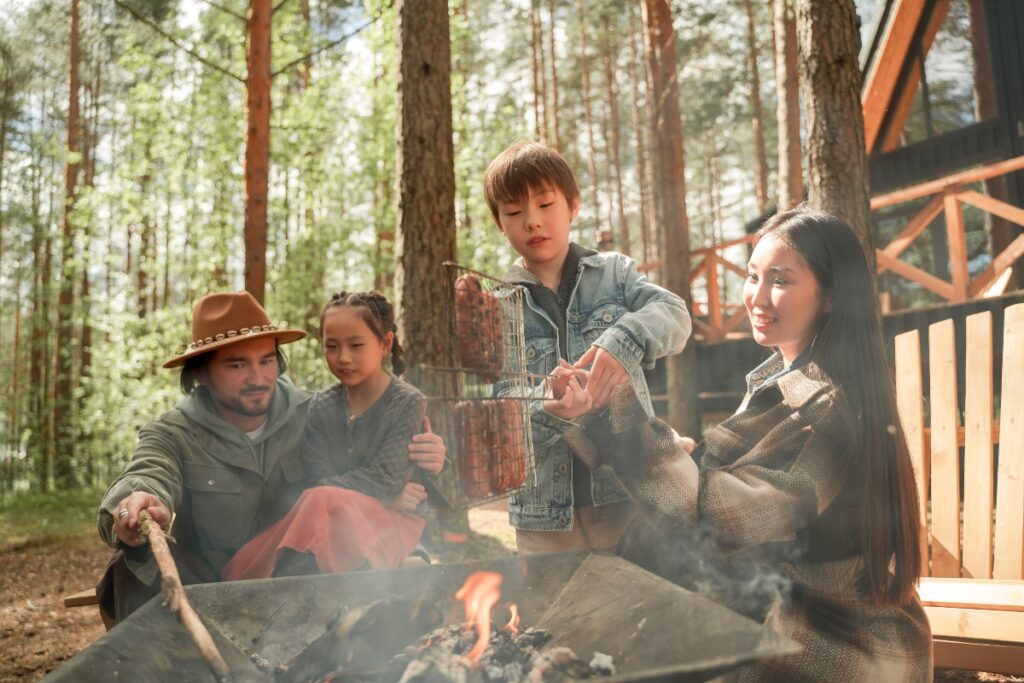  A family preparing sausages on a bonfire.
