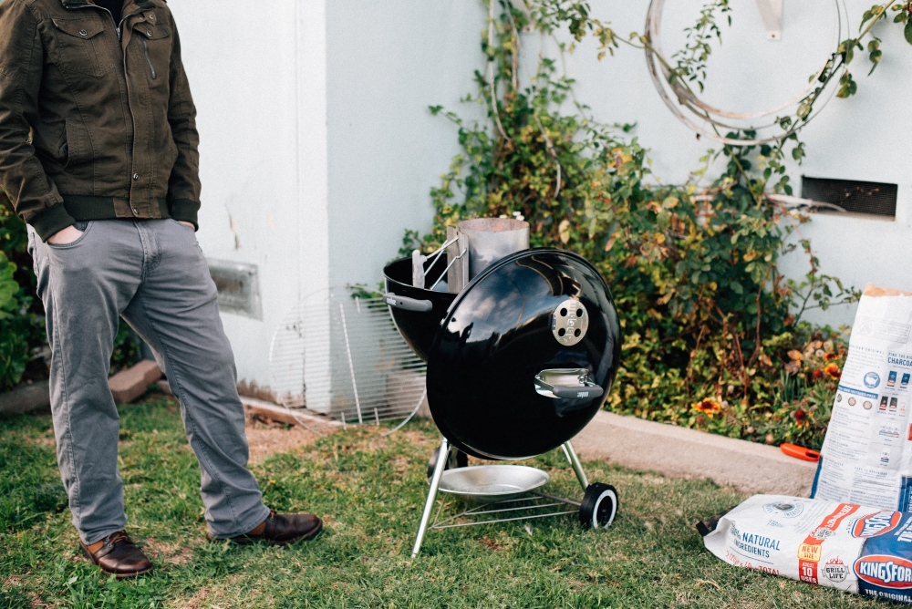 A man standing next to a black portable grill.