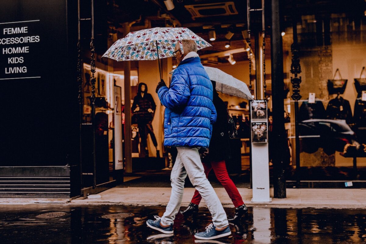 two people walking on the sidewalk on a rainy day